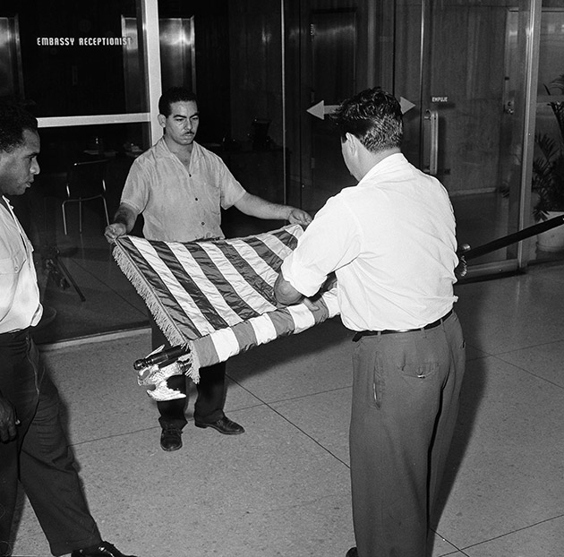 unidentified U.S. embassy employees rolling up a U.S. flag as the embassy transfers American affairs to the Swiss government, in Havana, Cuba. 