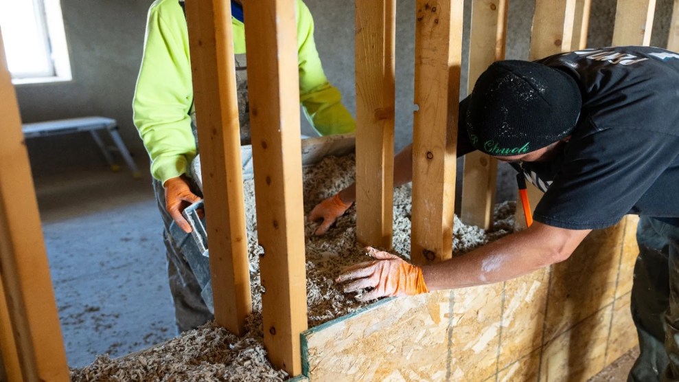 Two people working with saw materials to help build inside of a house