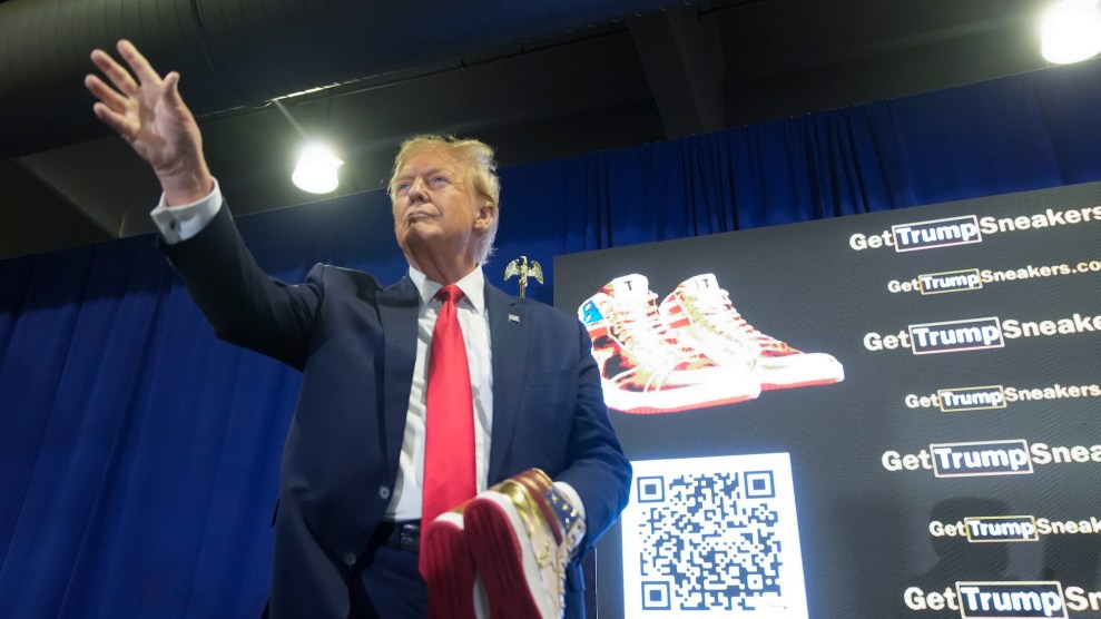 Donald Trump holds a pair of sneakers while speaking on a stage.