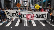 Protesters with a sign that says, "BlackRock, HoteAir, Climate"