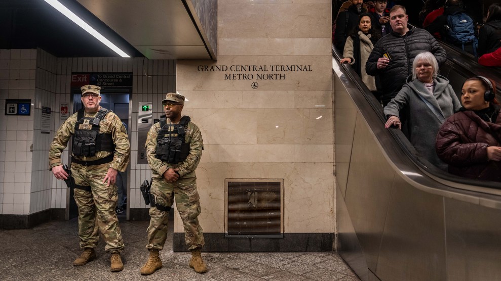 Two National Guard troops stand on patrol in New York's Grand Central Metro terminal, as commuters look on.