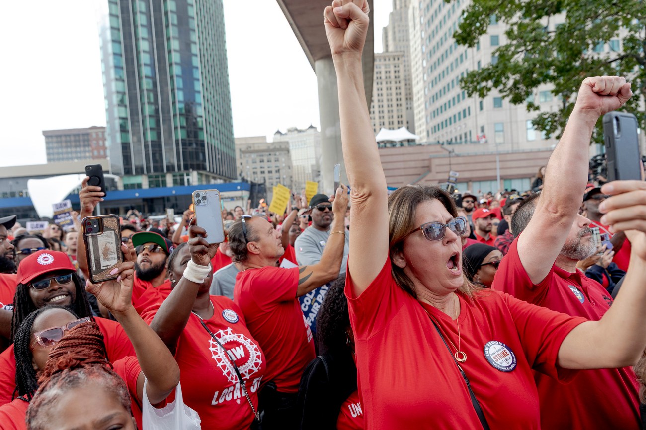 Large group of people in red shirts with upraised fists.