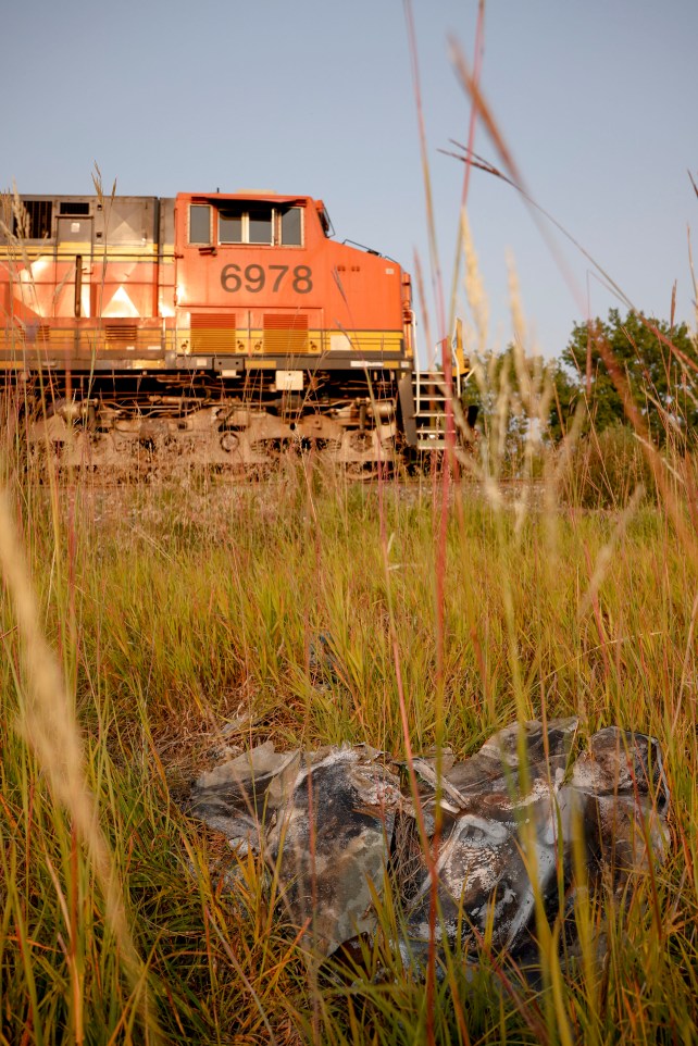 Train speeding past a homemade memorial in a field.