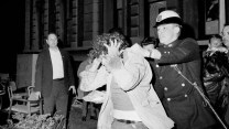 Black and white photo of a police officer removing a protester from a building.