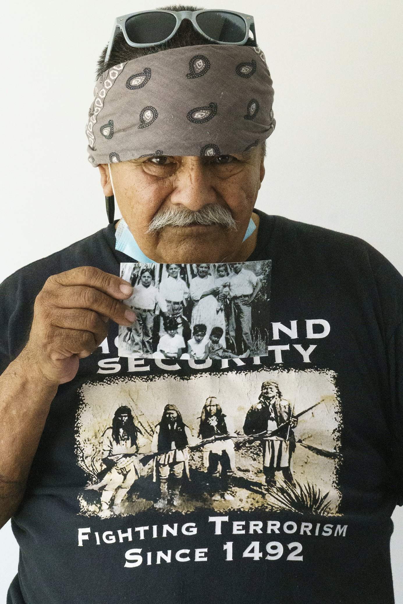 Man with a bandana on his head holding an old black and white photo.
