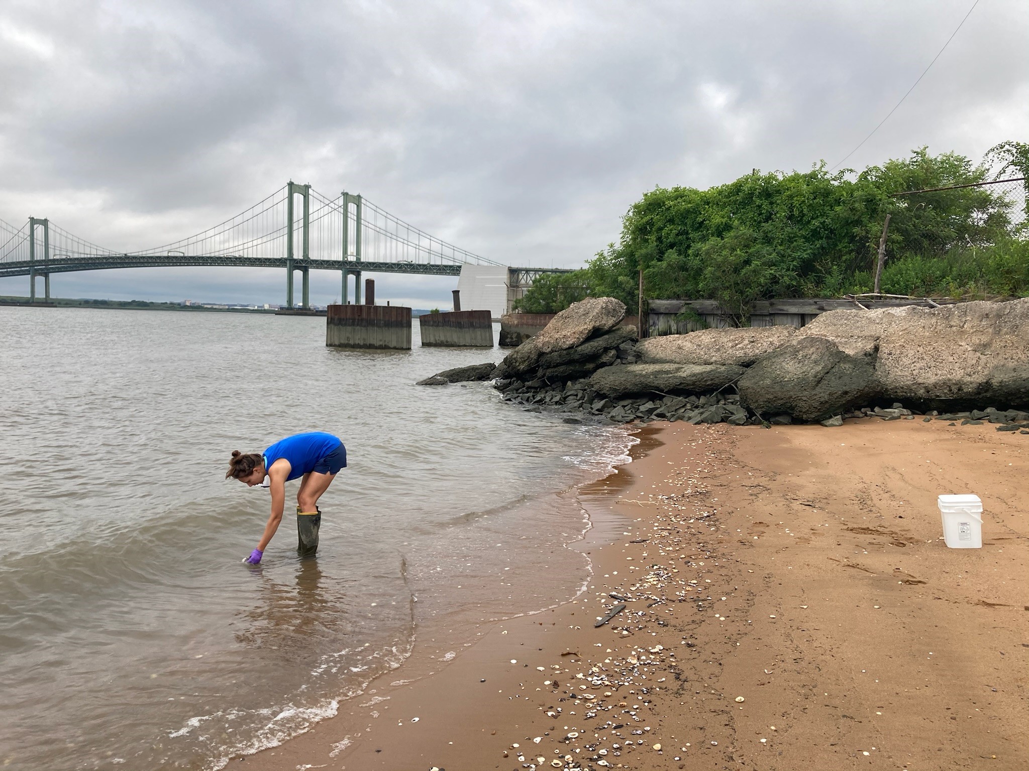 Woman bent over on a river beach. 