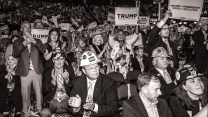 Crowd at RNC, man in front wearing a hard hat and a suit.