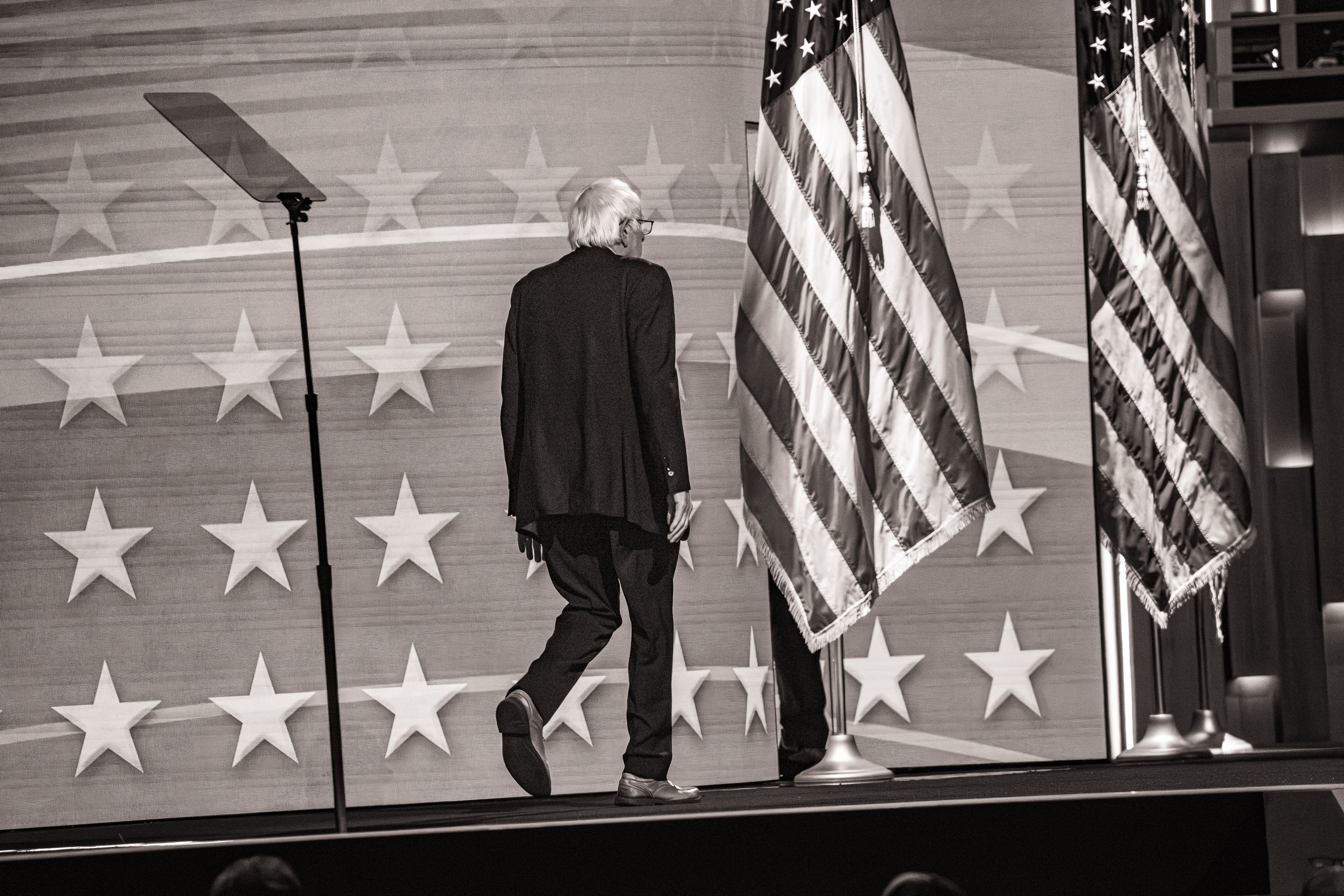 Black and white photo of Bernie Sanders walking off stage at the DNC.