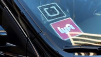 A photo of a black car with Uber and Lyft stickers