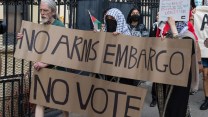 People hold a sign reading "no arms embargo, no vote"