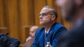 Wearing a blue suit, striped tie and glasses, Frank Artiles sits behind the counsel table, looking straight ahead with mute expression on his face.