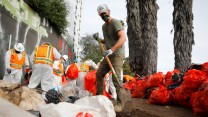 Gov. Gavin Newsom holds a shovel while cleaning up a homeless encampment.