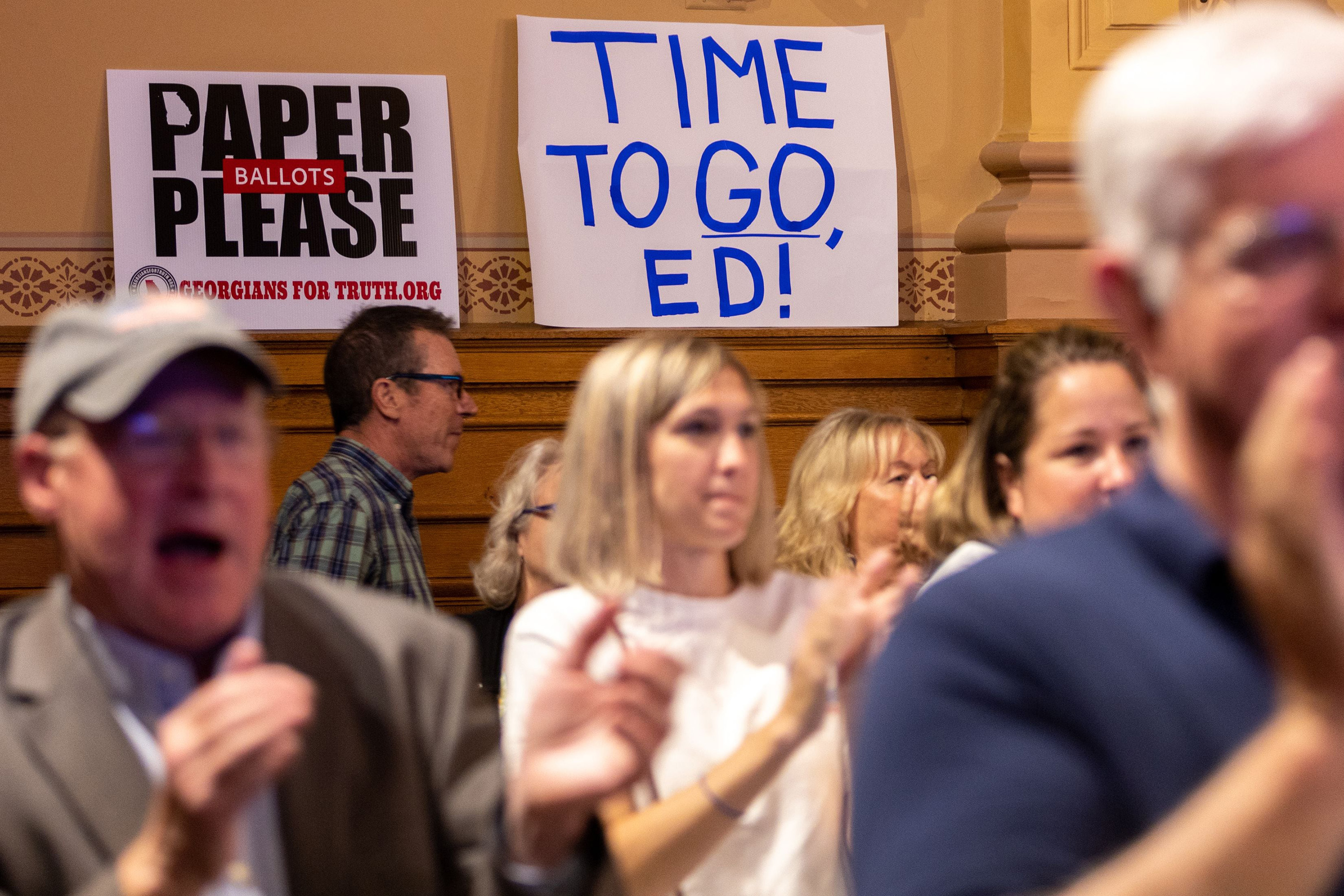 Meeting with signs reading, "Paper Ballots Please," and "Time to Go, Ed!"