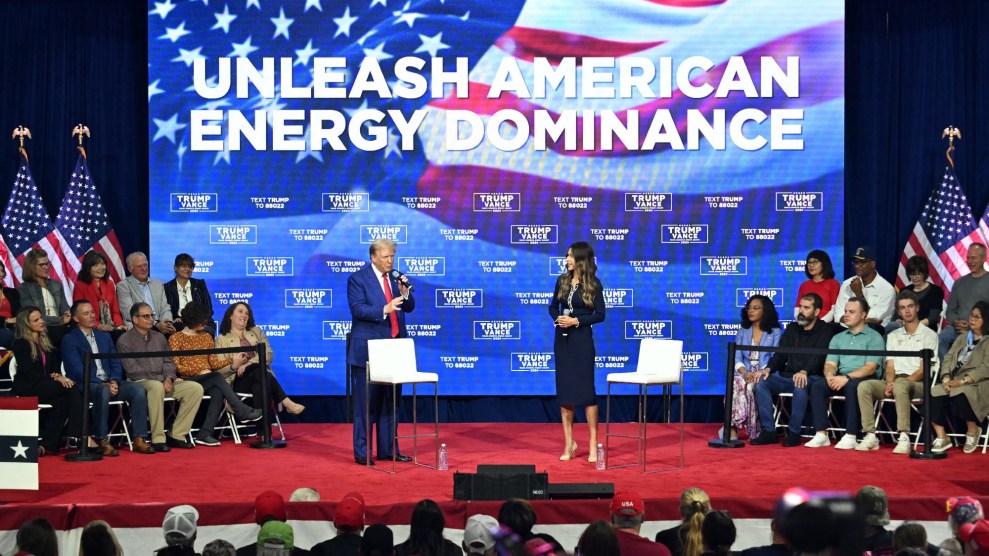 President Trump and South Dakota Governor Kristi Noem stand on a red stage in front of a screen that say Unleash American Energy Dominance