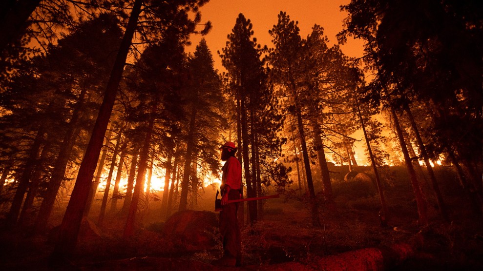 A fire fighter standings as trees are ablaze near him