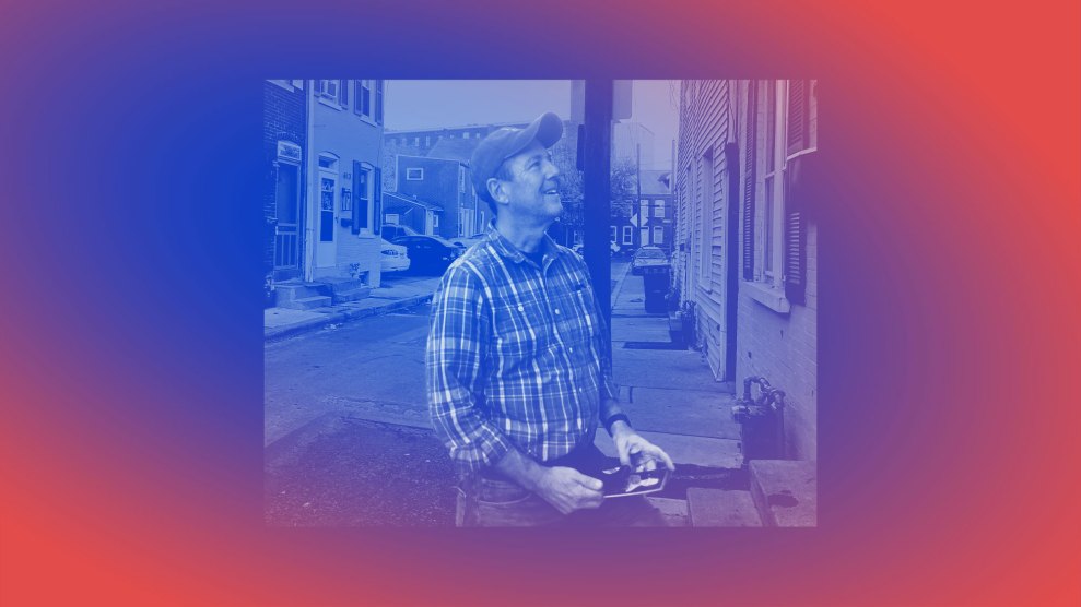 A man in front of a row of homes, canvassing. The man is wearing jeans, a plaid shirt and a baseball cap.