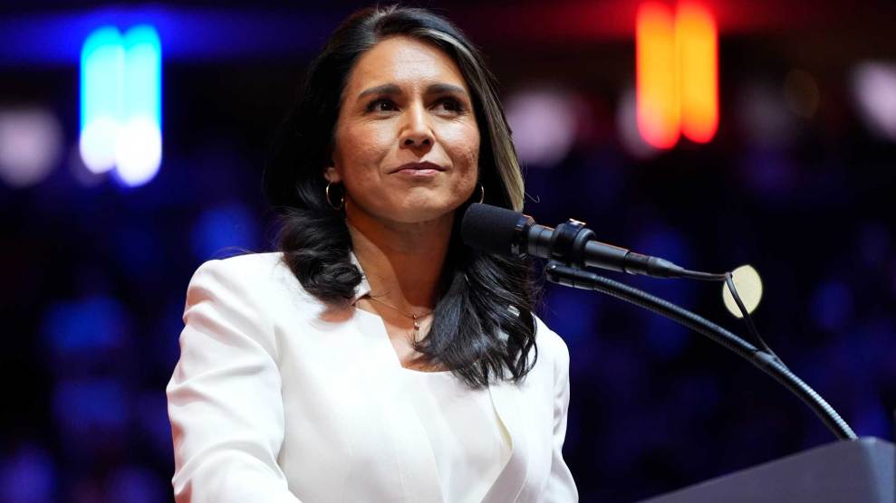 Tulsi Gabbard, wearing white jacket, speaking in front of a lectern