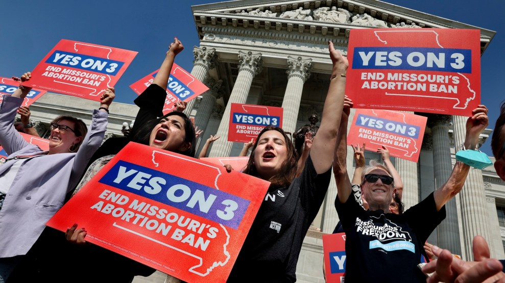 Abortion-rights protesters hold Yes on 3 signs.