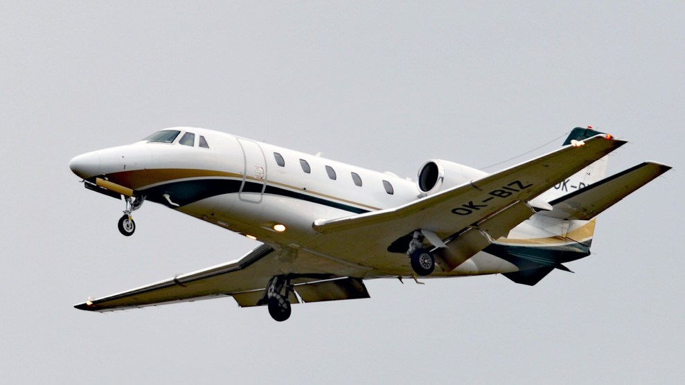 A private jet in the air with wheels out, ready to land