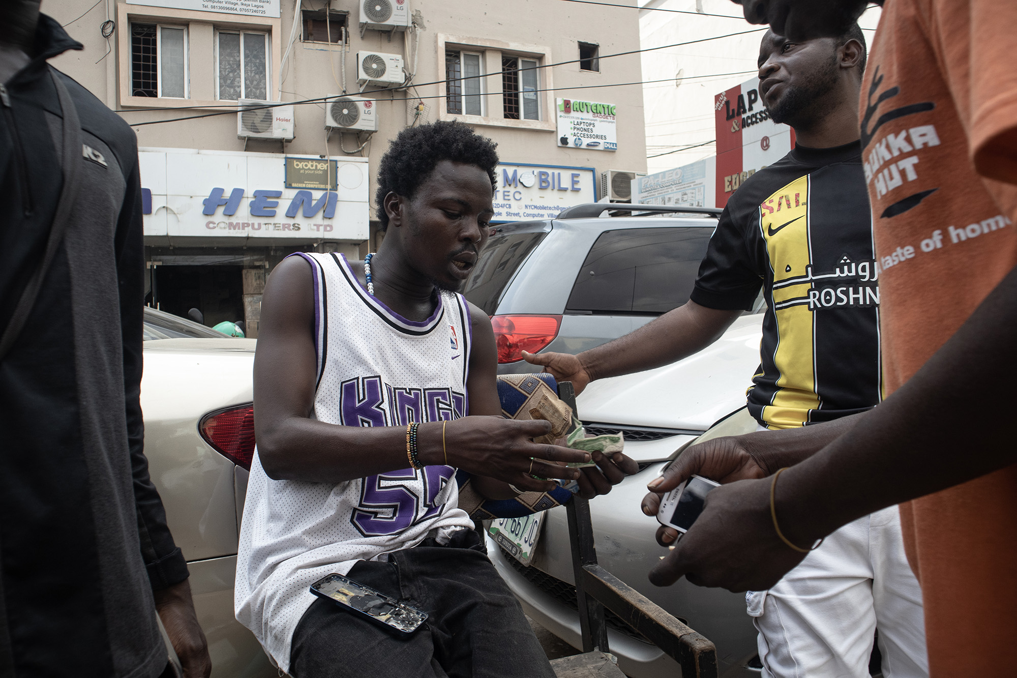 Man sitting in a chair, buying computer parts on the street.