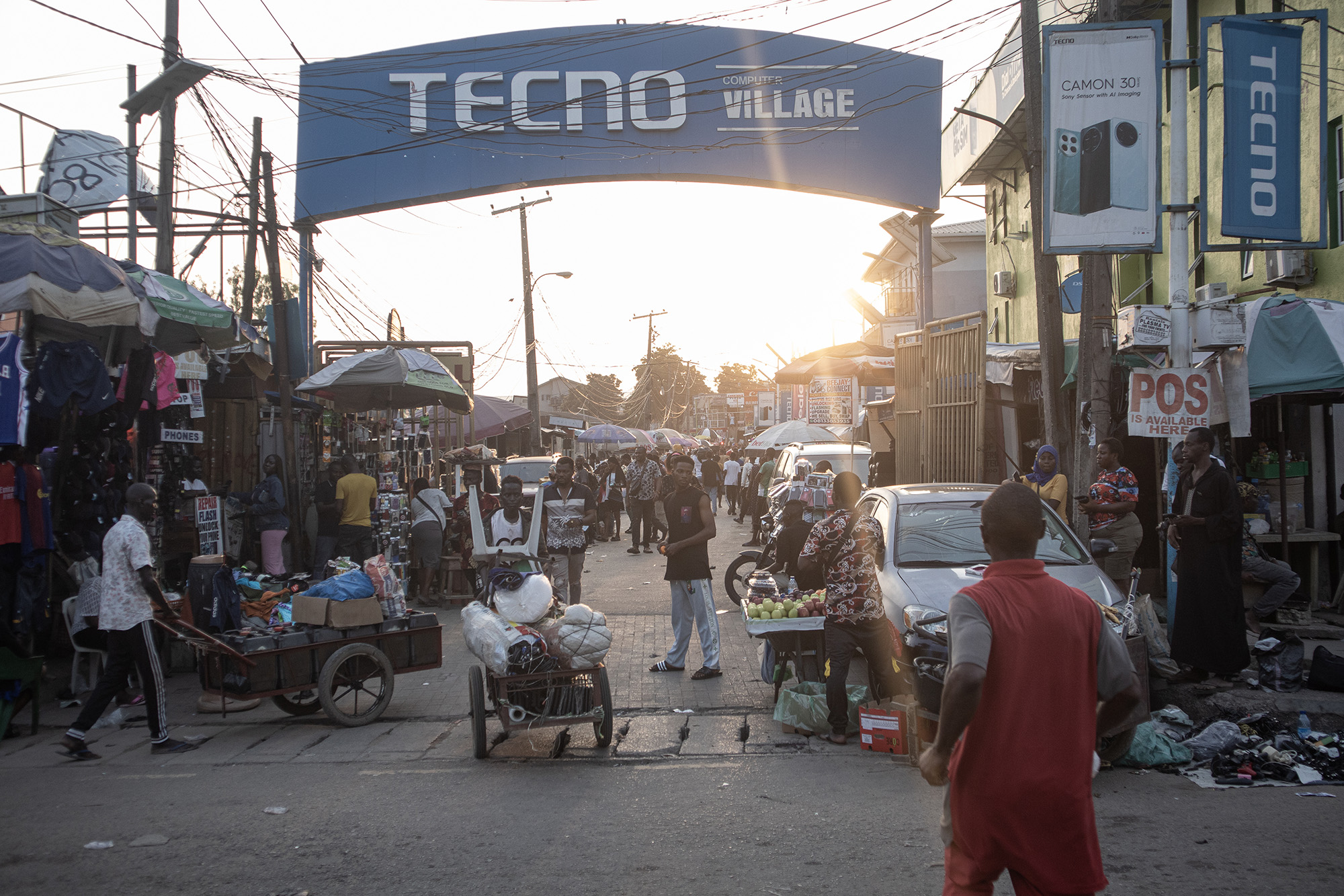 Busy street with a sign arching over it that reads, "Tecno Computer Village."