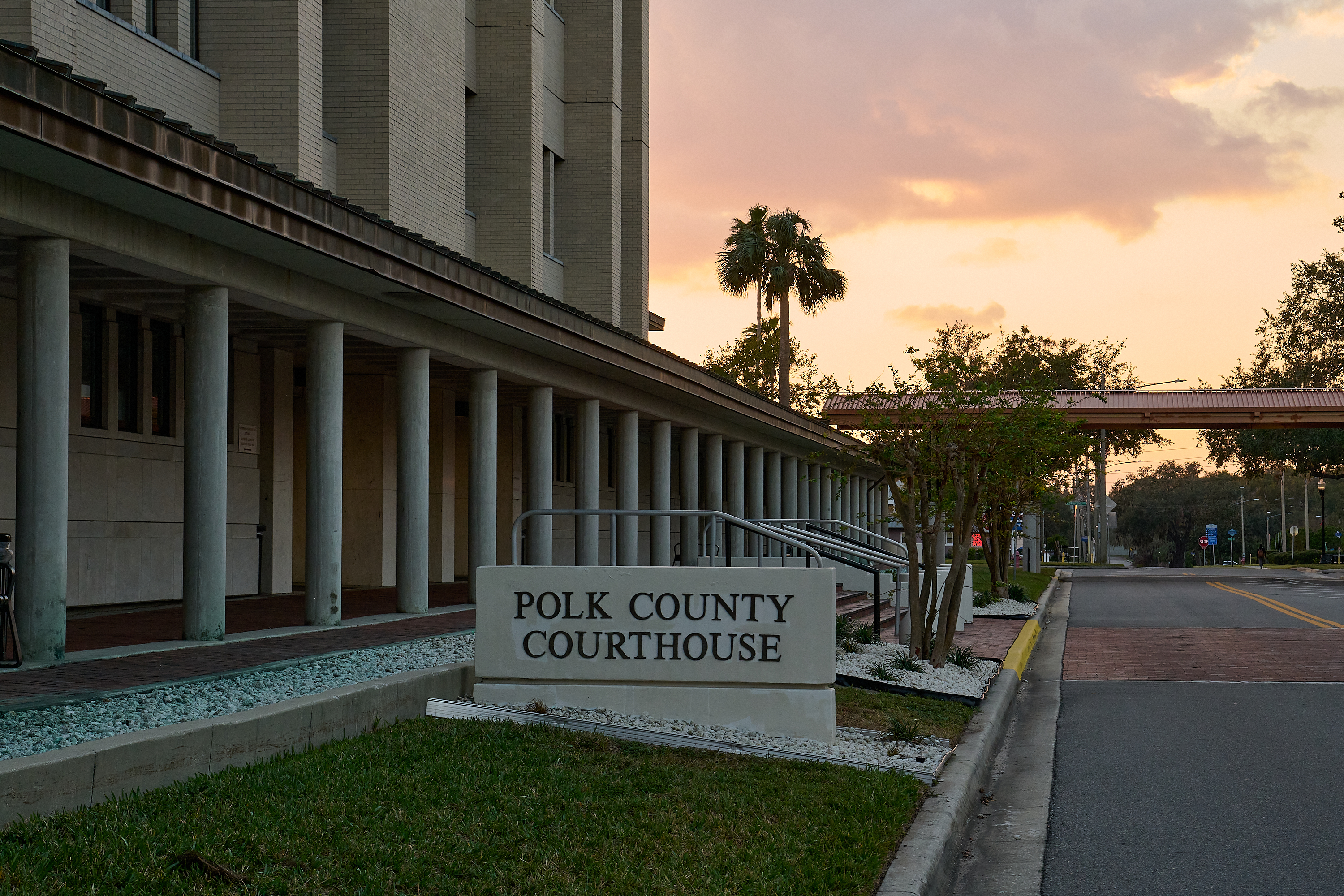 An exterior view of Polk County courthouse, with trees and a dimly lit sky in the background.