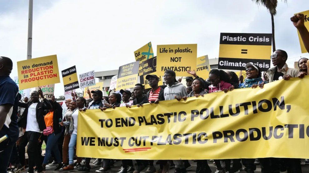 a group of protestors hold yellow signs about plastic crisis and pollution