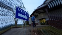 A voter walks out of a polling place after voting on November 5, 2024, in Rutledge, Georgia, with a large blue "VOTE" sign in front of him.