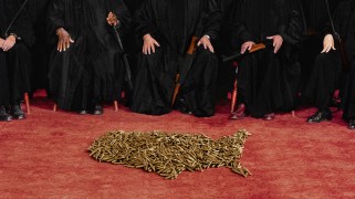 The hands and feet of five robed judges are visible in the background, each of them holding or resting a gun on their lap. In the foreground is an image of the United States shaped out of bullets.