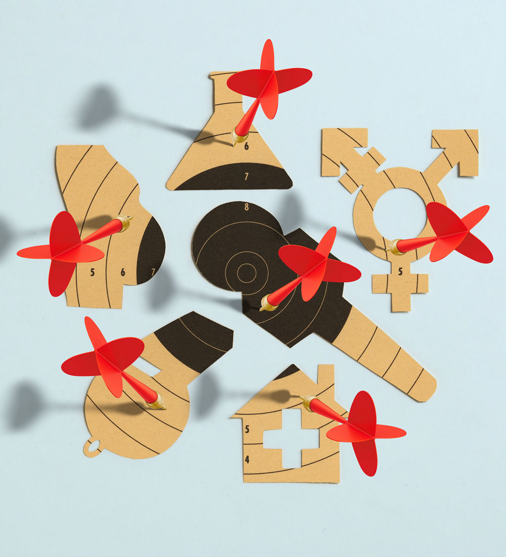 An illustration of red darts with gold tips going into cardboard cutouts of a house, a microphone, a pregnant person, a whistle, a lab jar and the transgender symbol.