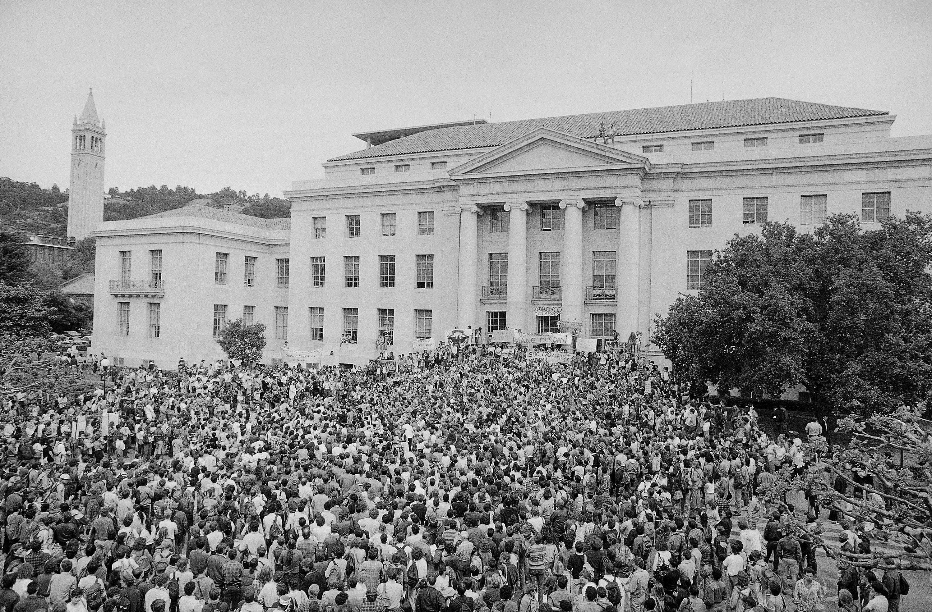 Large crowd of people surrounding a school building.