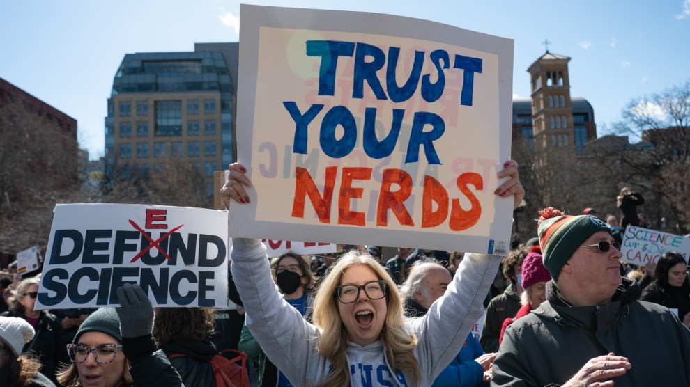 A smiling protester holds a "Trust Your Nerds" sign