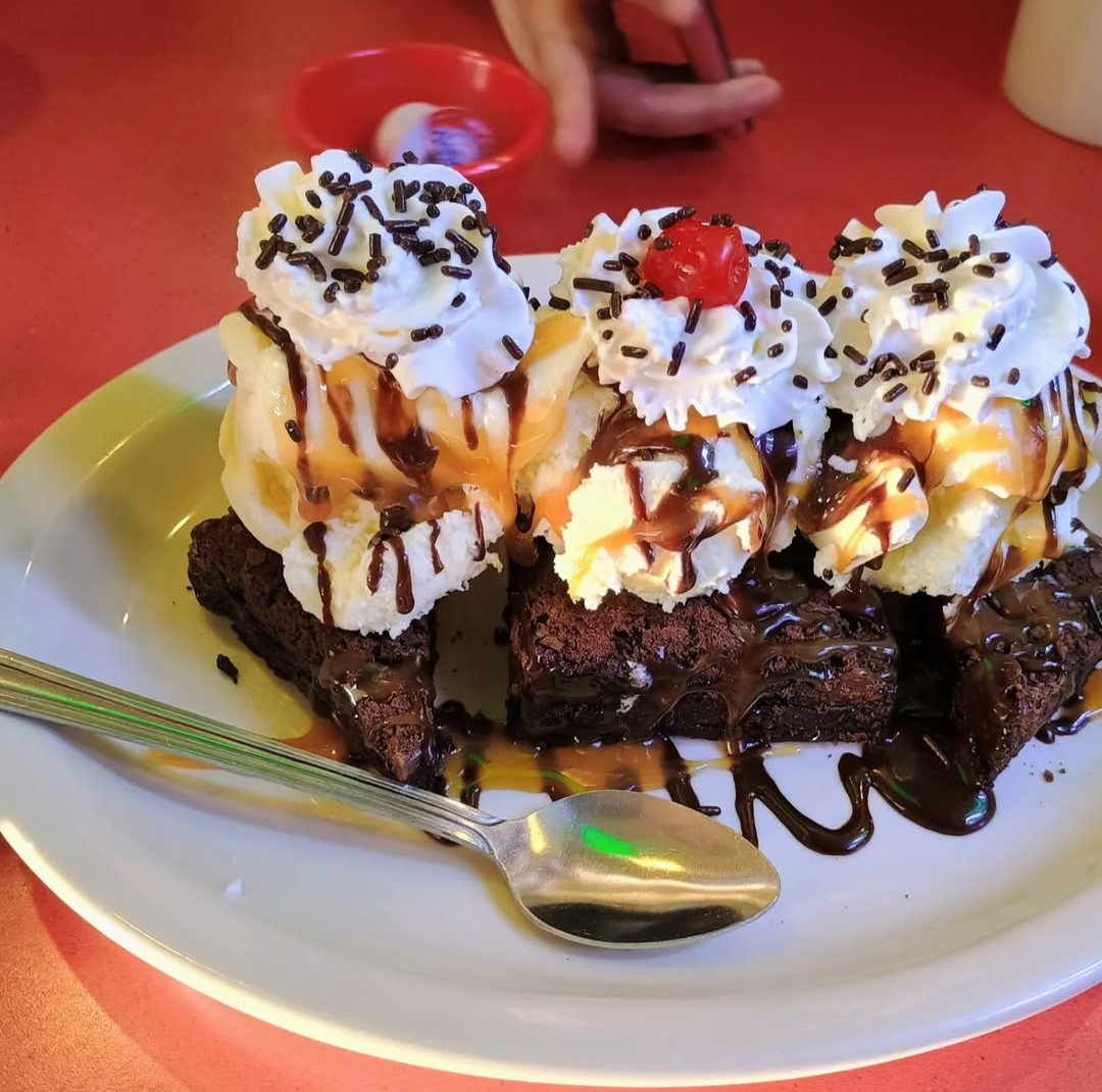 Brownie ice cream sundae on a plate with a spoon.