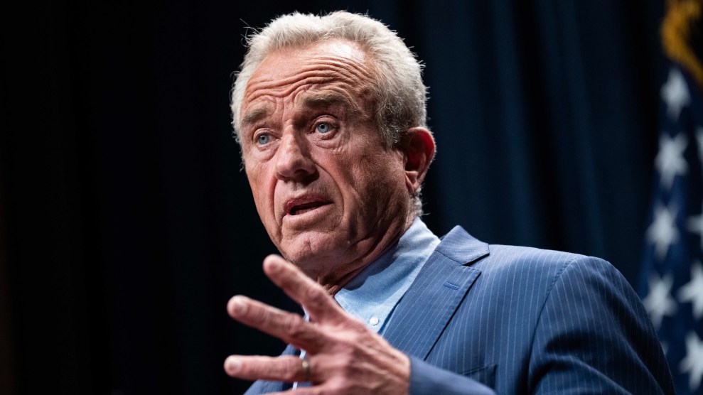RFK Jr with an outstretched hand while he's talking onstage in a suit