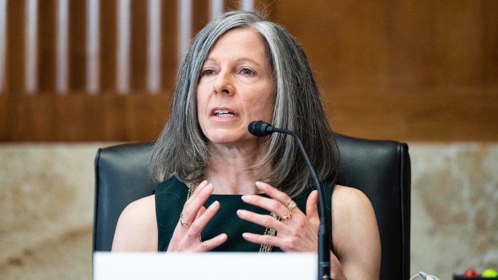 A white woman with grey hair sitting at a black chair.