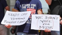 Protester holds a "Hands off Veterans Benefits and Jobs" and "We Didn't Vote for Elon" signs at the Market House in downtown Fayetteville, North Carolina as part of a nation wide "Hands Off!" protest against President Trump and Elon Musk on April 5th, 2025.