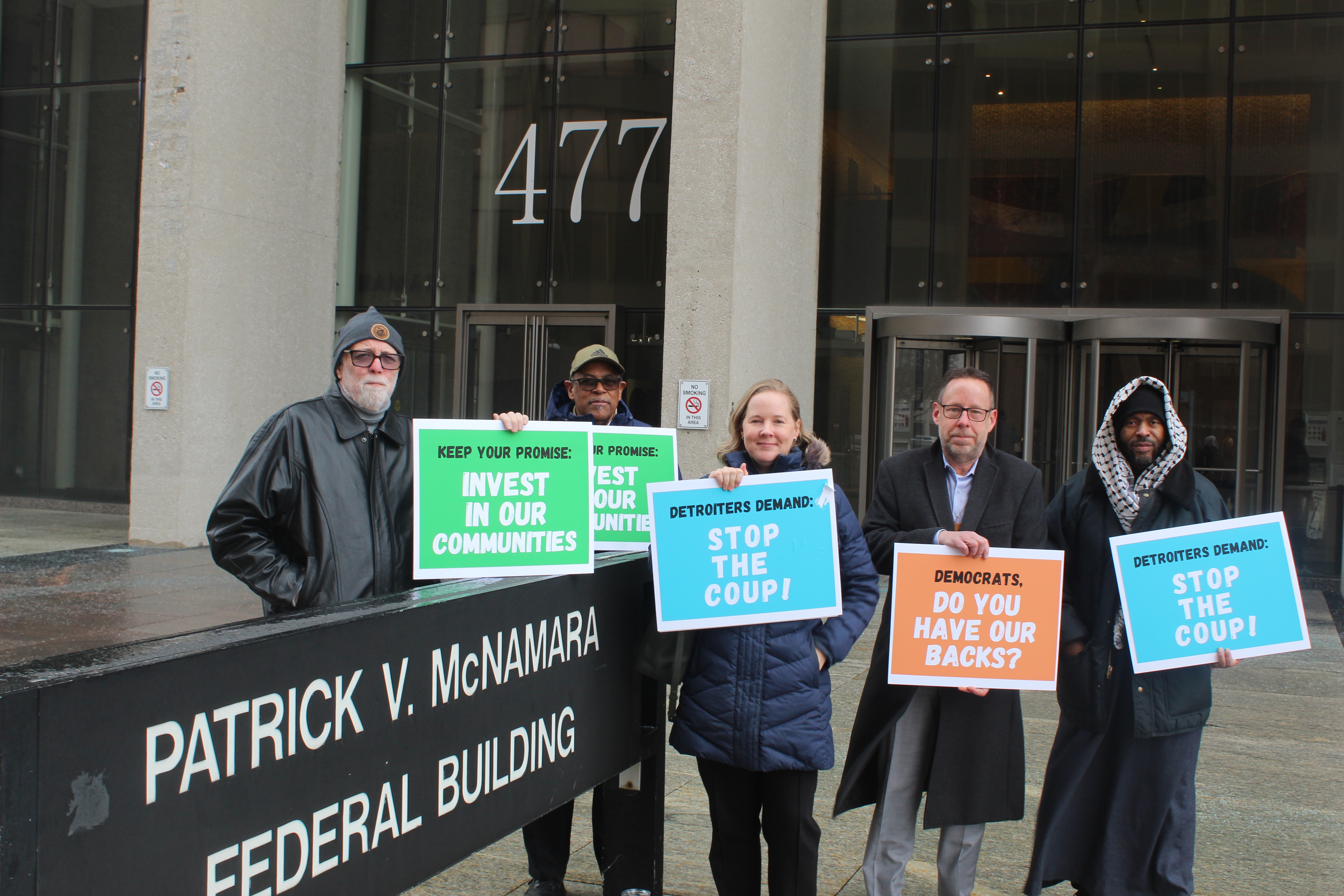 A group of people hold colorful signs asking for democratic help in support of clean energy.
