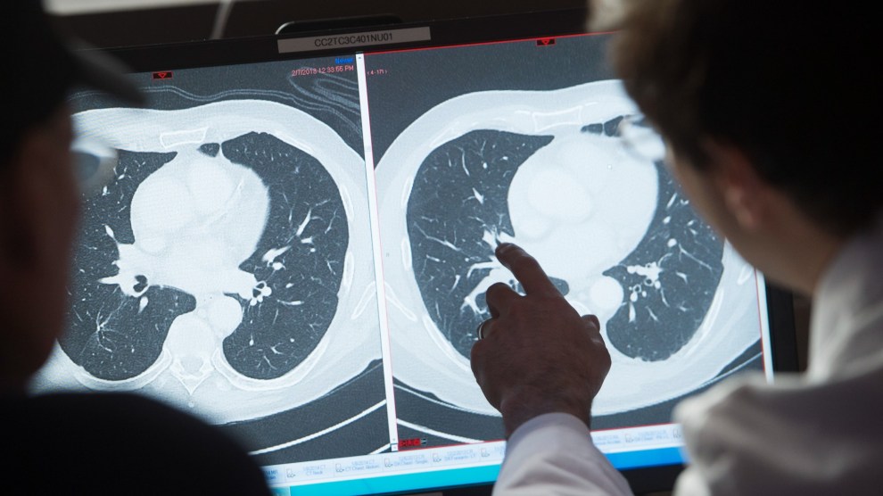 A scientists point to black and white images on a screen.