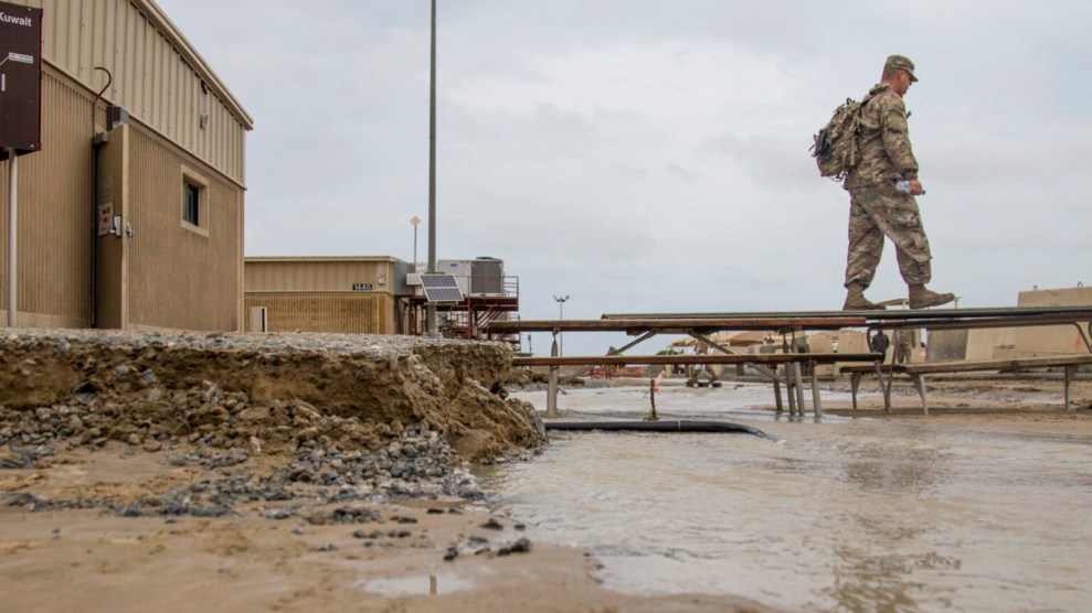 A soldier wearing a camouflage kit walks over a flooded area