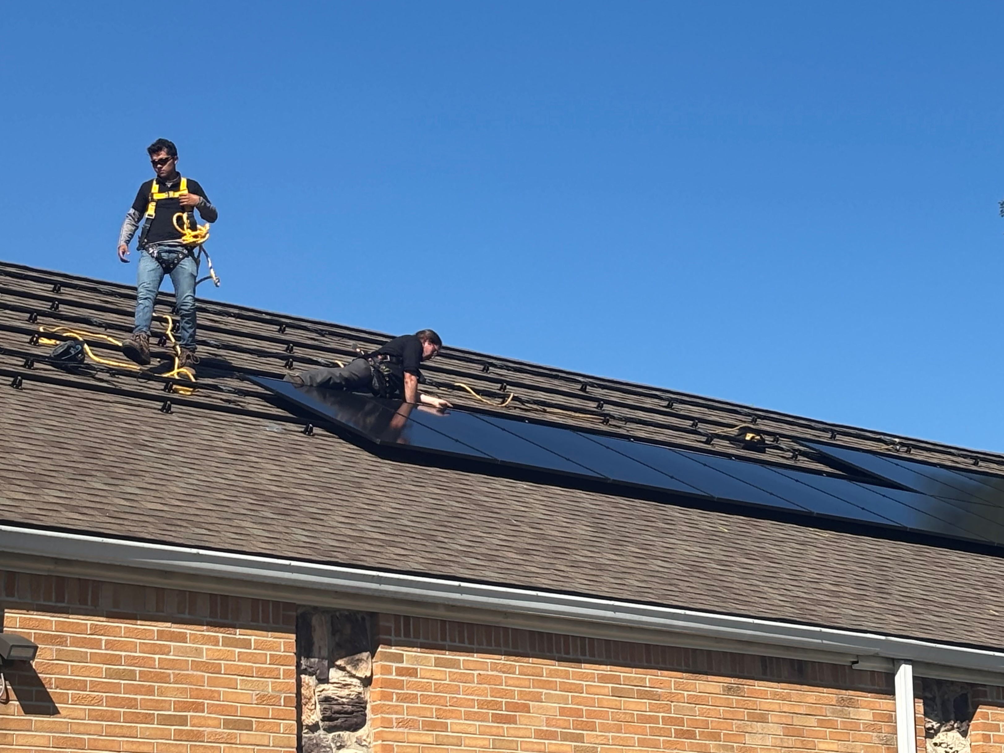 Two workers install solar on a roof