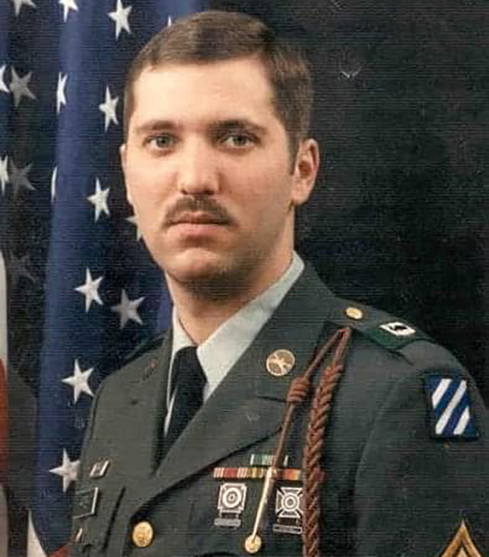 A formal portrait of a young James Harter, with brown mustache and short brown hair, in an Army dress uniform in front of an American flag.
