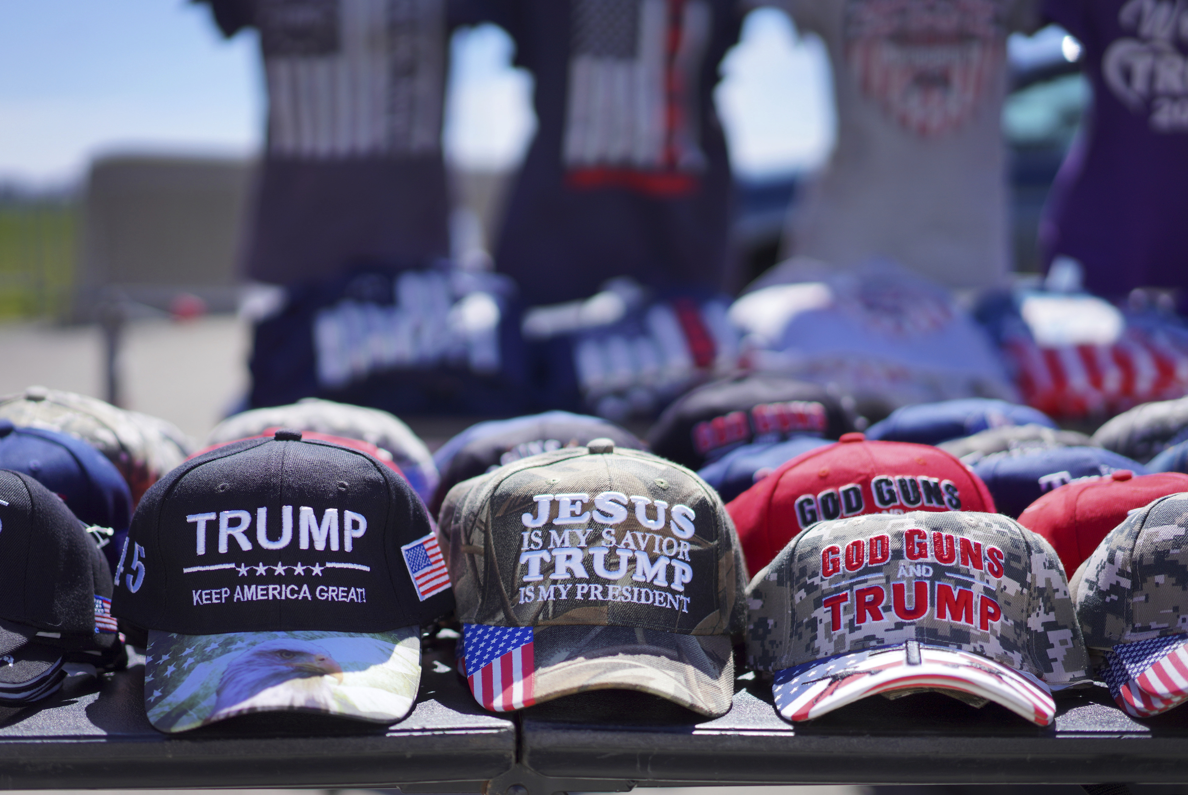 A table of baseball hats for sale in support of Donald Trump.