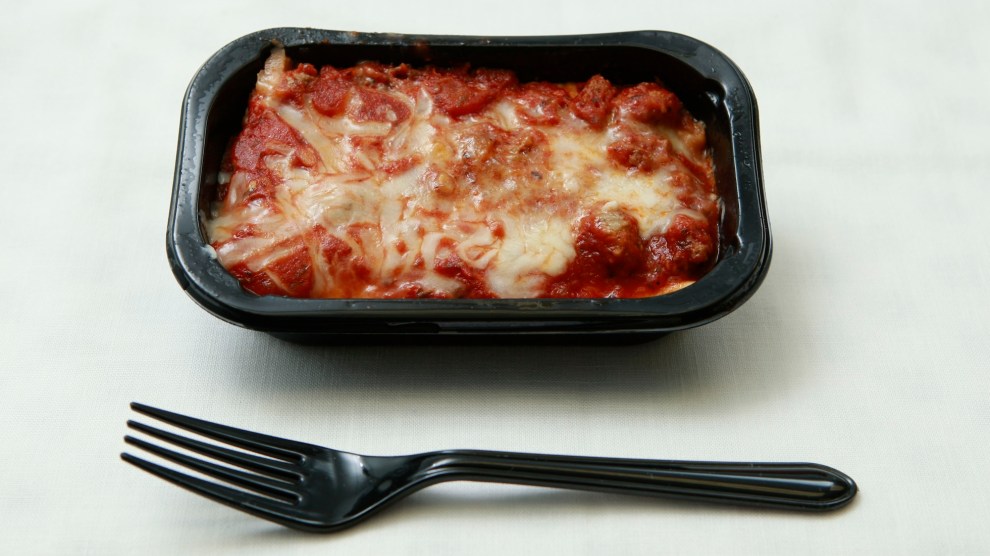 A black plastic container filled with tomato sauce and melted cheese on a white background with a black plastic fork in front of it.