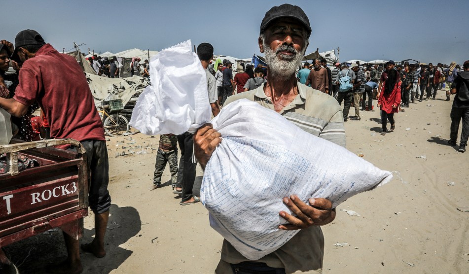 A man holds a sack of food in his hands at an aid site in Rafah.