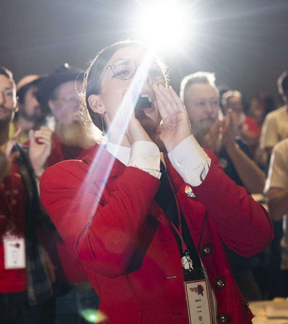Woman in red with hands cupped around her mouth, yelling.