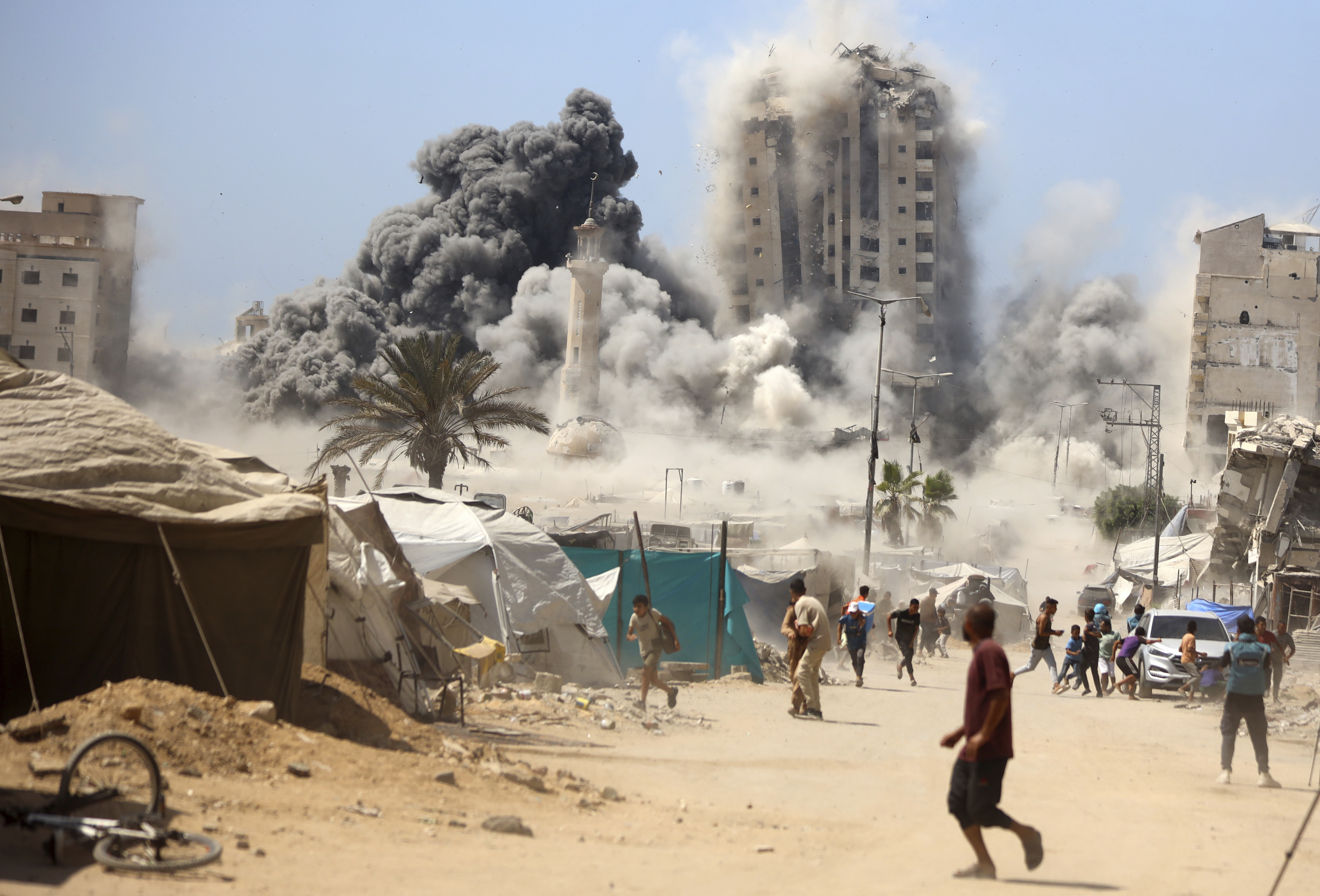 Smoke rises from an large building as it crumbles to the ground under Israeli airstrikes.