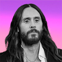 Black-and-white photo of a long-haired, bearded man set against a pink and purple background.