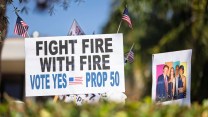 Signs at a protest in Santa Barbara support Proposition 50 in California