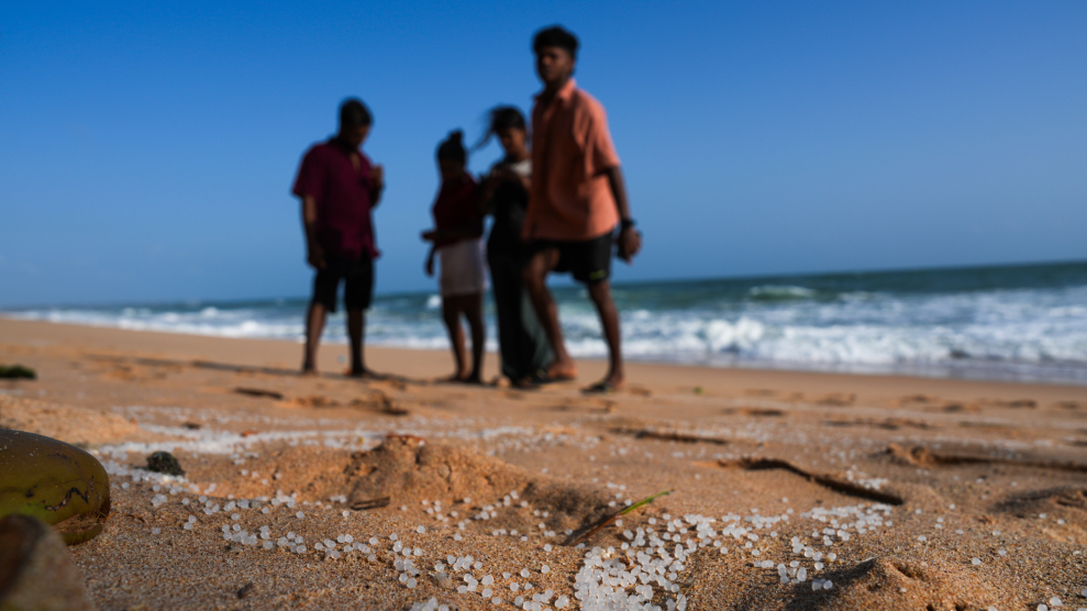 Small white plastic pieces mixed in with sand on a beach.