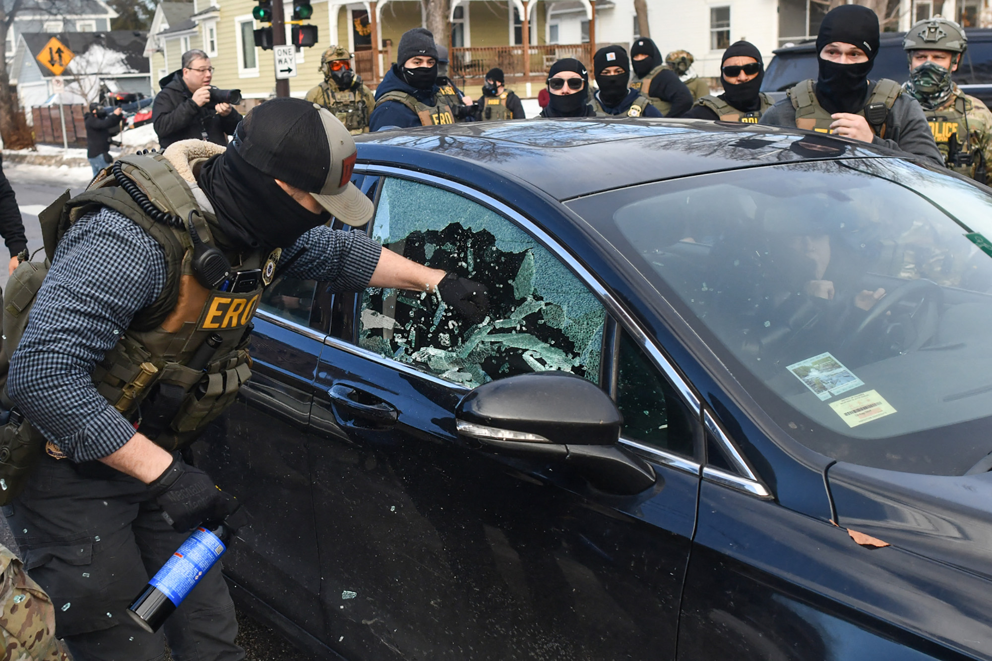 A federal agent smashes a car window.